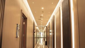 Un largo pasillo bien iluminado con puertas a ambos lados, que conduce a habitaciones.