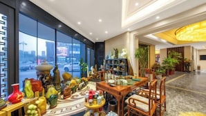Un vestíbulo con un ventanal grande, una mesa de recepción y varios objetos decorativos.