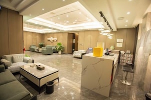 Un vestíbulo de hotel con zonas de estar, un mostrador de recepción y un bar.