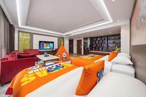 Een hotelkamer met twee bedden, een televisie, een bank en een boekenplank.
