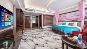 Habitación de hotel con una cama grande, un televisor de pantalla plana, piso con diseño de mármol y vista al cielo a través de la ventana.