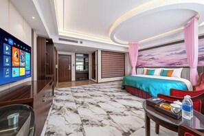 Een hotelkamer met een groot bed, een flatscreen-tv, een vloer met een marmerpatroon en uitzicht op de lucht door het raam.
