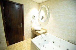A bathroom with a dark wooden door, a white sink with a round mirror, and a large bathtub. - Hanwu International Hotel (Wuwei Pedestrian Street Branch) (Wuwei)