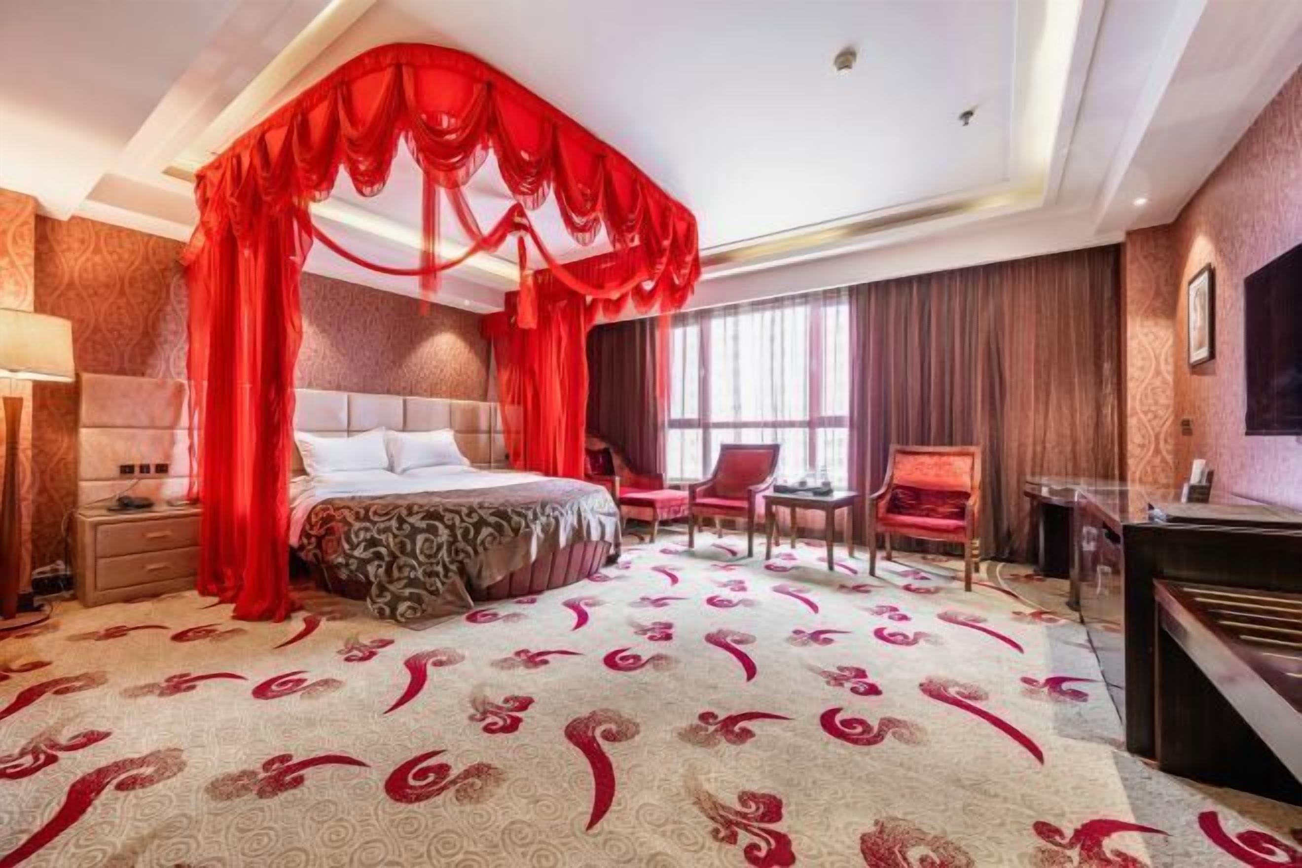 A hotel room with a large bed, a desk, a chair, and a TV.