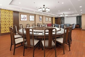A conference room with a round table, chairs, a projector screen, and a presentation screen.
