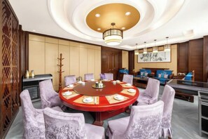 A conference room with a round table, chairs, and a chandelier.