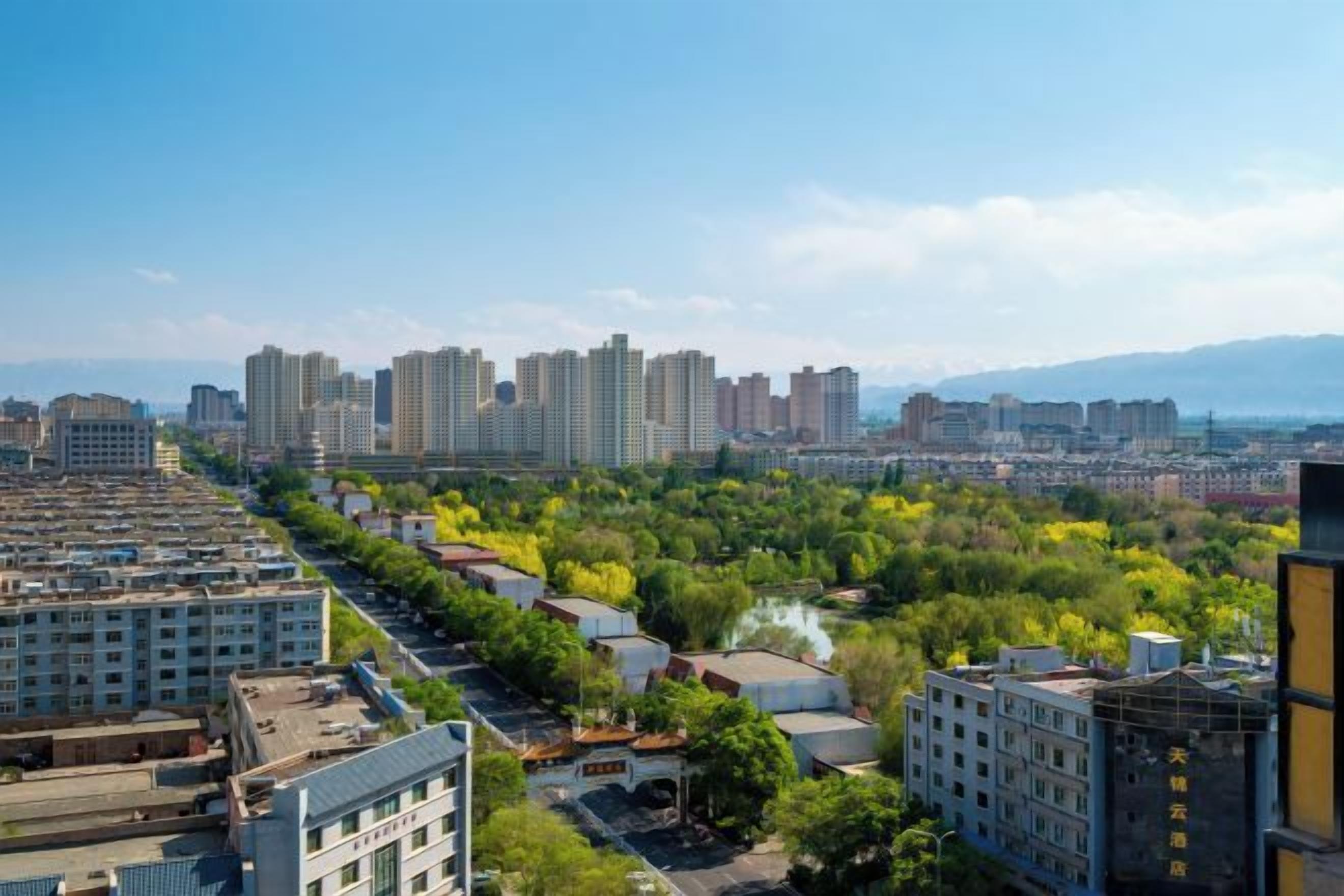 A cityscape with high-rise buildings, a river, and a mix of greenery and urban development.