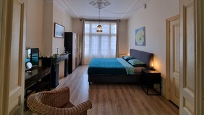 Et soveværelse med seng, sengebord, lampe, stol og et skrivebord med computer samt dekorative genstande.