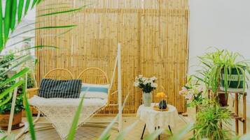 Una habitación con una cama, una mesita con un florero y plantas en macetas.