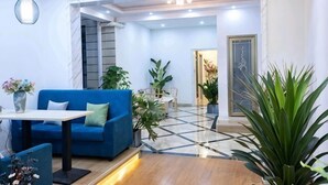 A modern lobby with a blue sofa, a coffee table, and potted plants. - Hongye Inn (Dujiangyan)