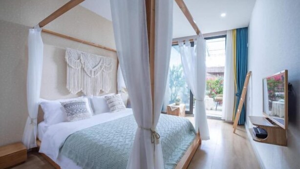 A bedroom with a four-poster bed, a television, and a view of the outdoors. - Hongye Inn (Dujiangyan)