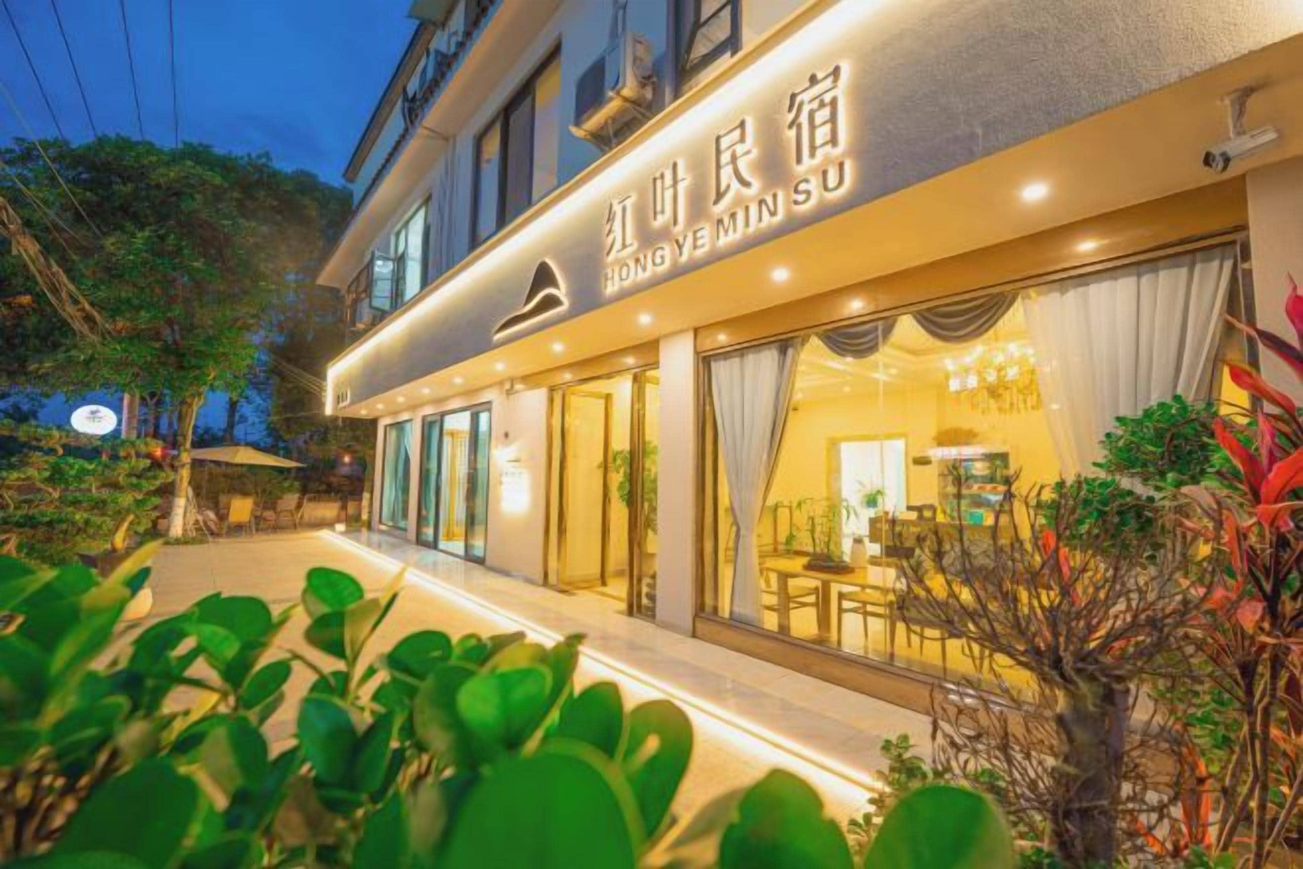 A hotel with a well-lit exterior, large windows, and a visible dining area inside.