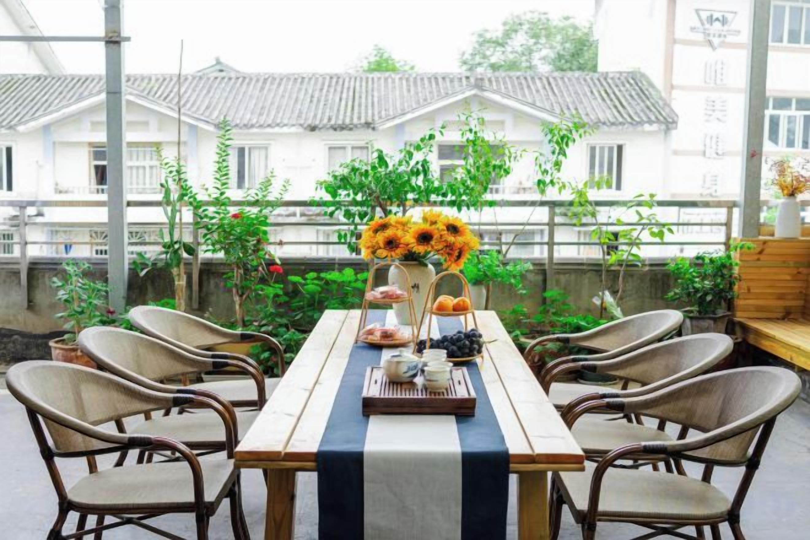 Een terras met een tafel voor vier personen, omringd door rieten stoelen, en een uitzicht op traditionele gebouwen op de achtergrond.