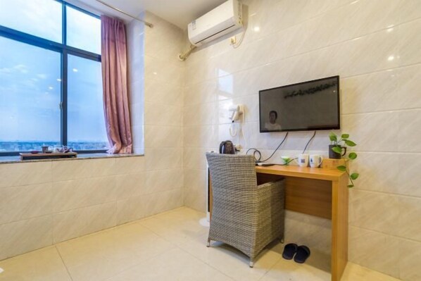 A modern room with a large window, a desk with a chair, a flat-screen TV, and a small plant. - Jiangdao Hostel (Jiangmen)