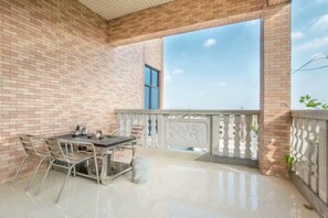 An outdoor balcony with a table and chairs, a view of the sky, and a brick wall. - Jiangdao Hostel (Jiangmen)