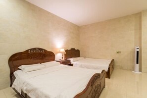 A hotel room with two wooden beds, a bedside table with a lamp, and a wall-mounted air conditioning unit. - Jiangdao Hostel (Jiangmen)