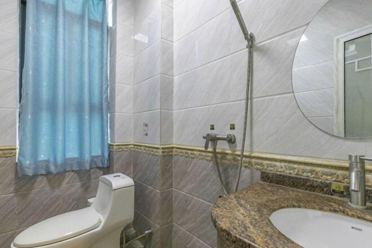 A bathroom with a toilet, shower, and sink.