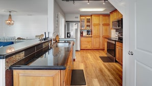 A modern kitchen with wooden cabinets, a granite countertop, and stainless steel appliances. - 4 Bed/3 Bath North Cape San Blas Beach Front Home - Steps to the Water!! (Port St. Joe)