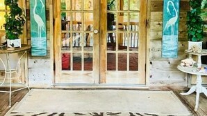 Une cabane en bois avec un grand tapis orné de motifs d’arbres, des portes en bois et deux tableaux représentant des oiseaux, accrochés au mur.