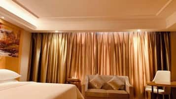 A hotel room with a bed, a sofa, a table, and curtains.