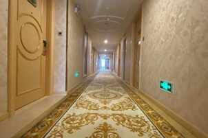 Un pasillo largo y estrecho con alfombra de diseño intrincado y paredes color crema.