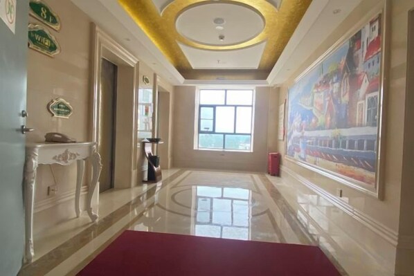 A hotel hallway with a red carpet, a painting on the wall, and a ceiling with a circular design.
