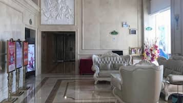 Un vestíbulo con piso de mármol, un mostrador de recepción y una zona de estar con sillones tapizados.
