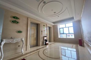 A spacious lobby with a marble floor, a decorative console table, and a large window providing natural light. - Vienna Hotel (Jieyang Longwei) (Jieyang)