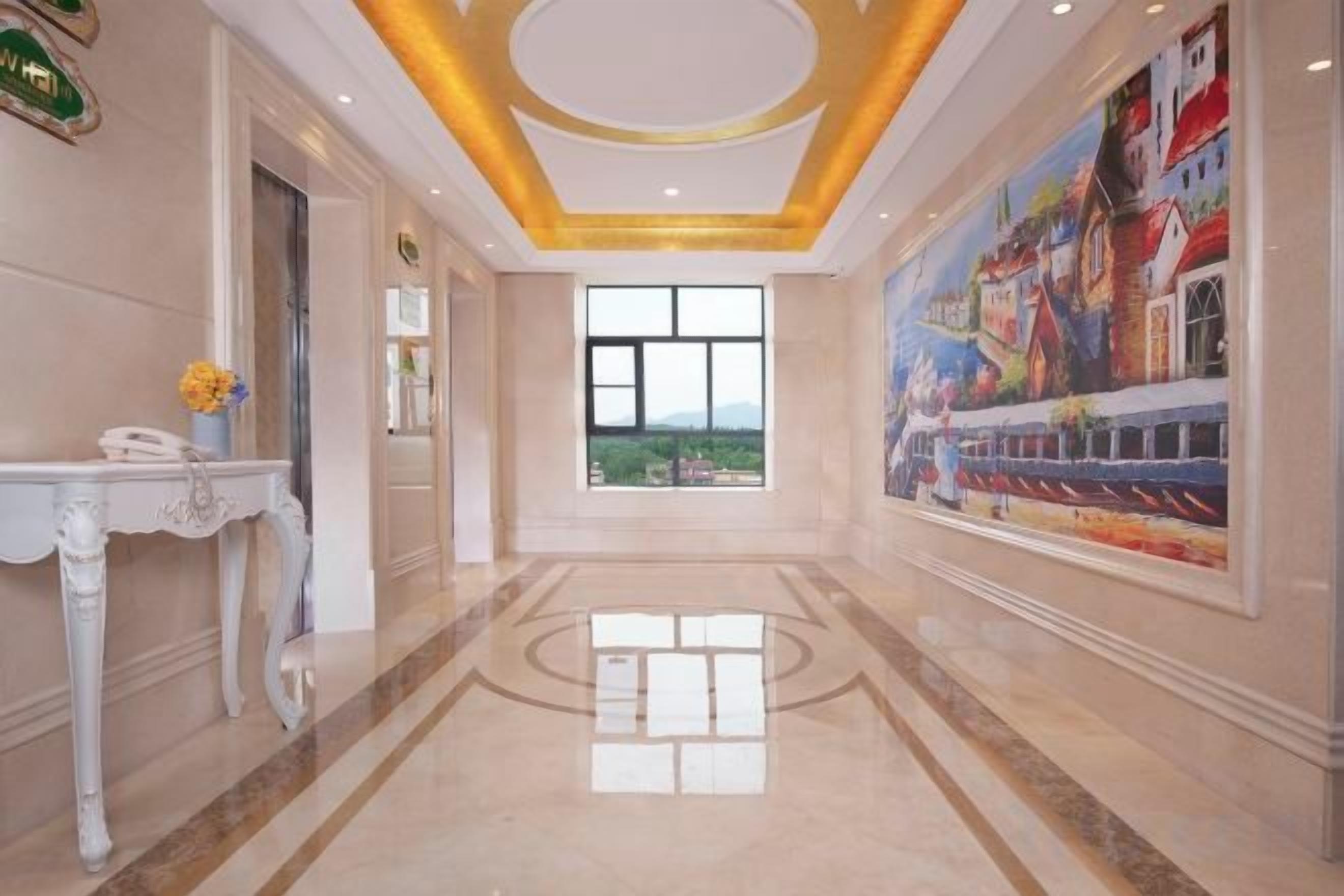 Un vestíbulo de hotel con piso de mármol, una recepción y un ventanal con vistas.