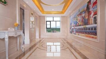 Un vestíbulo de hotel con piso de mármol, una recepción y un ventanal con vistas.