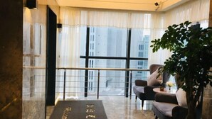 Un hall d'hotel modern amb taulell de recepció, zona de seients i grans finestres que donen vista a la ciutat.