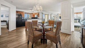 A modern kitchen with a dining area featuring wicker chairs and a glass table. - Blue Heron Pointe | Lakeview | Pool | Hot Tub |Gym (Invermere)