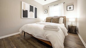 A bedroom with a bed, a ceiling fan, a bedside lamp, and a framed picture on the wall. - Speedway Luxe | Hot Tub | Shuffle | Steps to Track (Indianapolis)