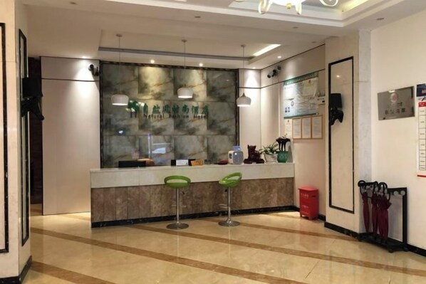 A reception area with a marble counter, green bar stools, and a wall-mounted display.