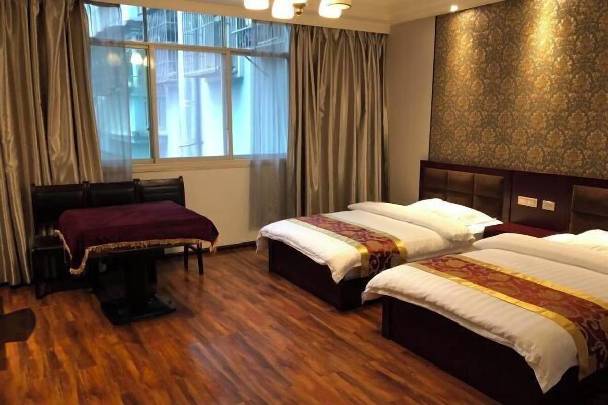 Een hotelkamer met twee bedden, een bureau en een groot raam met gordijnen.