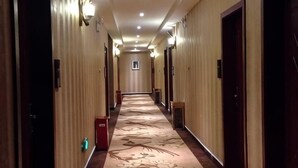 A hotel hallway with carpeted floors, wooden walls, and doors on both sides. - Ziranfeng Fashion Hotel (Congjiang Food Street) (Congjiang)