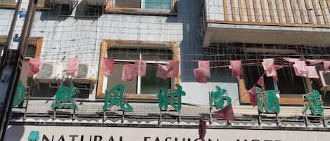 Um hotel com uma placa que diz 'NATURAL FASHION HOTEL' e caracteres chineses acima.
