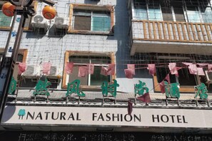 Ein Hotel mit einem Schild, auf dem 'NATURAL FASHION HOTEL' und chinesische Schriftzeichen stehen.