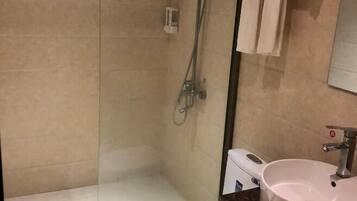 A bathroom with a glass shower enclosure, a white sink, and a mirror.