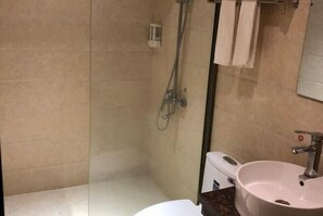 Une salle de bain avec une douche à parois de verre, un lavabo blanc et un miroir.