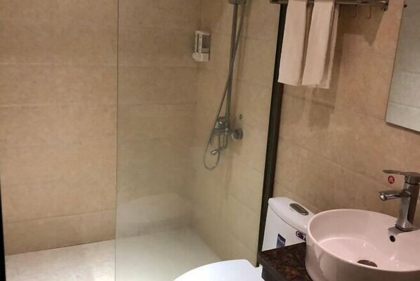 Ein Badezimmer mit Duschkabine aus Glas, einem weißen Waschbecken und einem Spiegel.