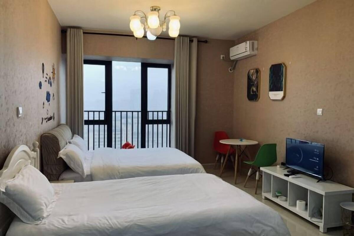 Une chambre d’hôtel avec deux lits, une télévision, une petite table et un balcon avec des rideaux.