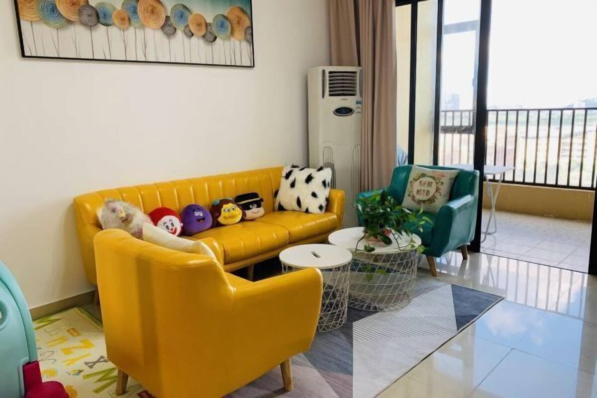 Un salon avec un canapé jaune, un fauteuil vert et une petite table sur laquelle est posée une plante.