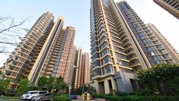 A high-rise residential building with multiple balconies, a parking area, and a gated entrance. - Meet Sunshine Holiday Apartment (Zhuhai Hengqin) (Zhuhai)