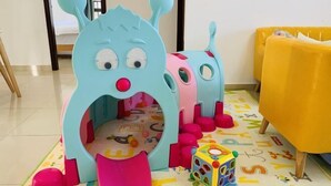 A children's play area with a blue and pink playhouse, a colorful cube toy, and alphabet-patterned floor mats. - Meet Sunshine Holiday Apartment (Zhuhai Hengqin) (Zhuhai)