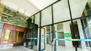A modern hotel entrance with glass doors, a digital check-in kiosk, and a tiled floor. - Meet Sunshine Holiday Apartment (Zhuhai Hengqin) (Zhuhai)