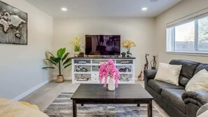 A modern living room with a flat-screen TV, a sofa, a coffee table, and decorative items. - Gameroom and Theater in a breathtaking home (Centennial)