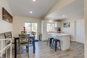 A modern kitchen with a central island, a dining area with a table and chairs, and a view of the outdoors. - Gameroom and Theater in a breathtaking home (Centennial)