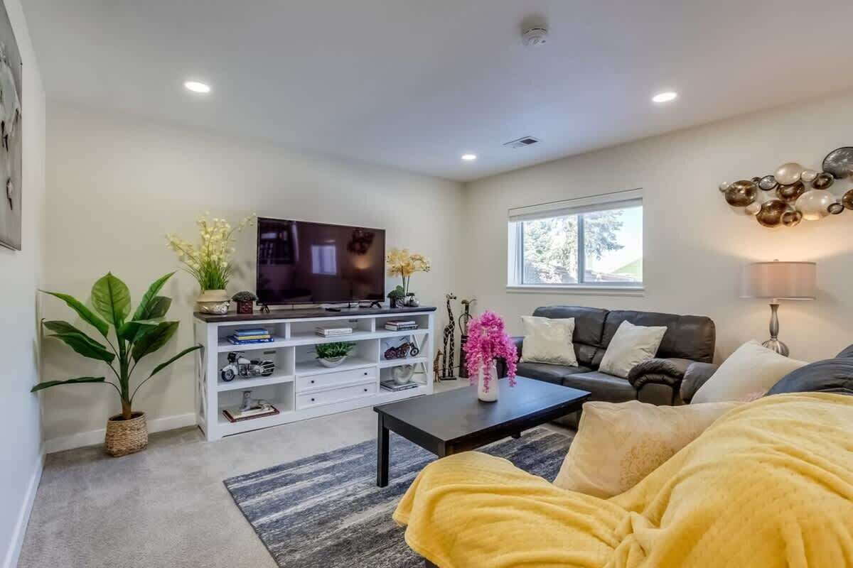 Een moderne woonkamer met een flatscreen televisie, een bank, een salontafel en een boekenkast.