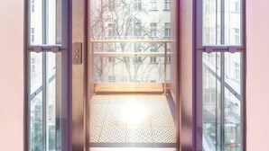 An elevator with a glass enclosure, a digital display showing the number 4, and a patterned floor. - S42 Hotel Prague (Prague)